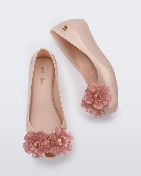 Side and top view of a pair of pearly pink Ultragirl Springtime kids flat with two clear pink flowers and peep toe.