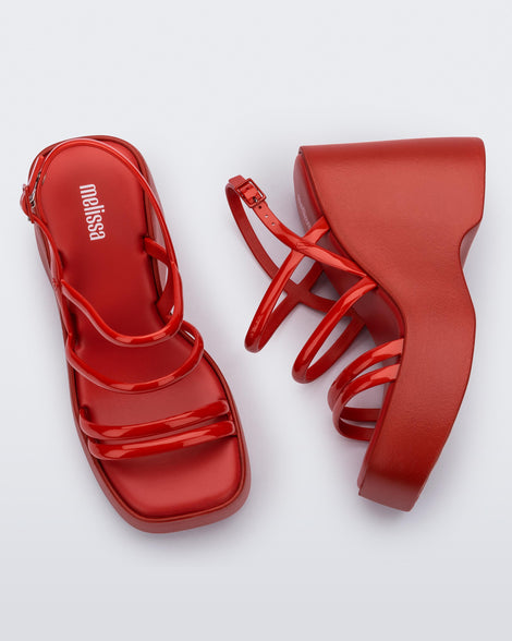 Side and top view of a pair of red Jessie platform wedge sandals with side buckle ankle strap