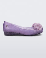 Side view of a clear glitter purple Ultragirl Springtime kids flat with two purple flowers and peep toe.