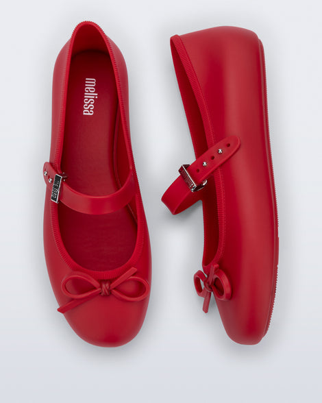 Side and top view of a pair of red Soft Ballerina Delicate Bow flats with top strap and bow