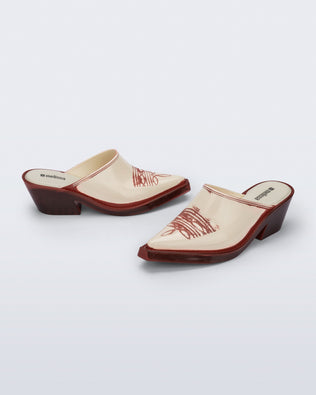Side and angled view of a pair of beige with red heel and accents Texas Mule heels