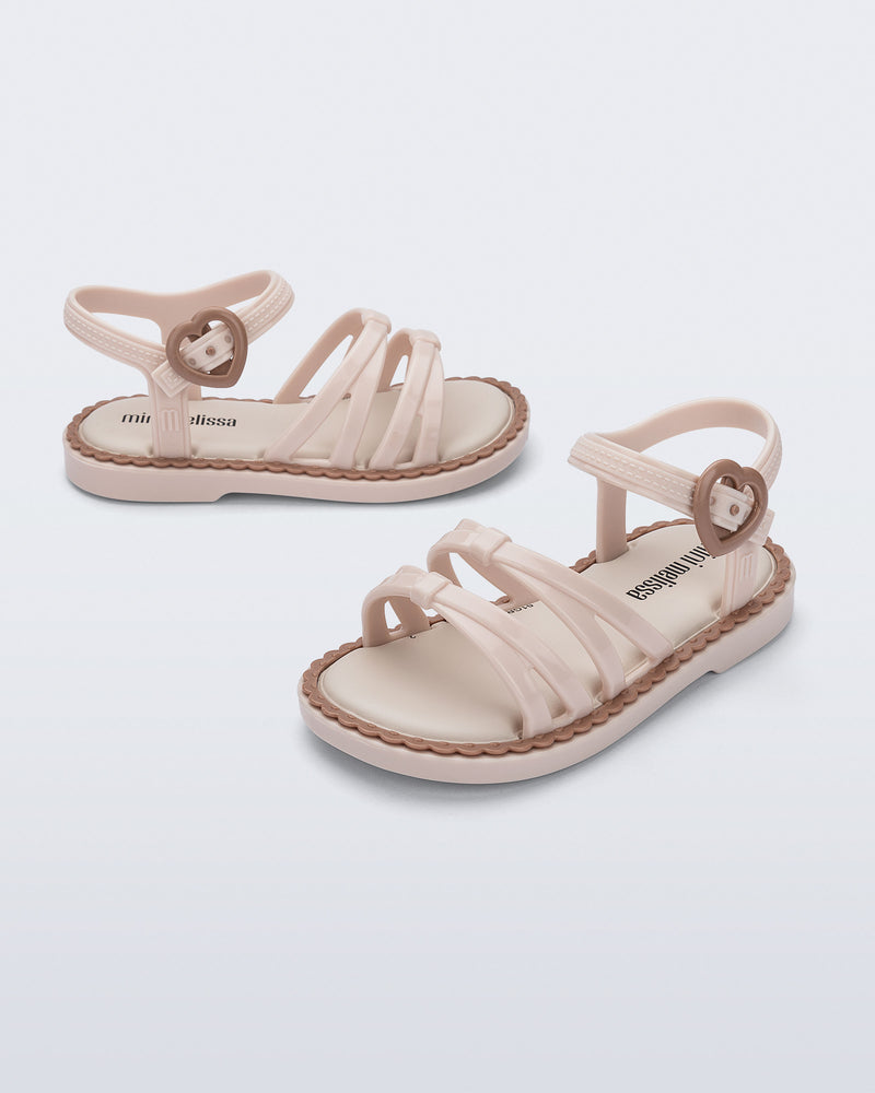 Side and angled view of a pair of beige Aurora baby sandals with brown trim and buckle