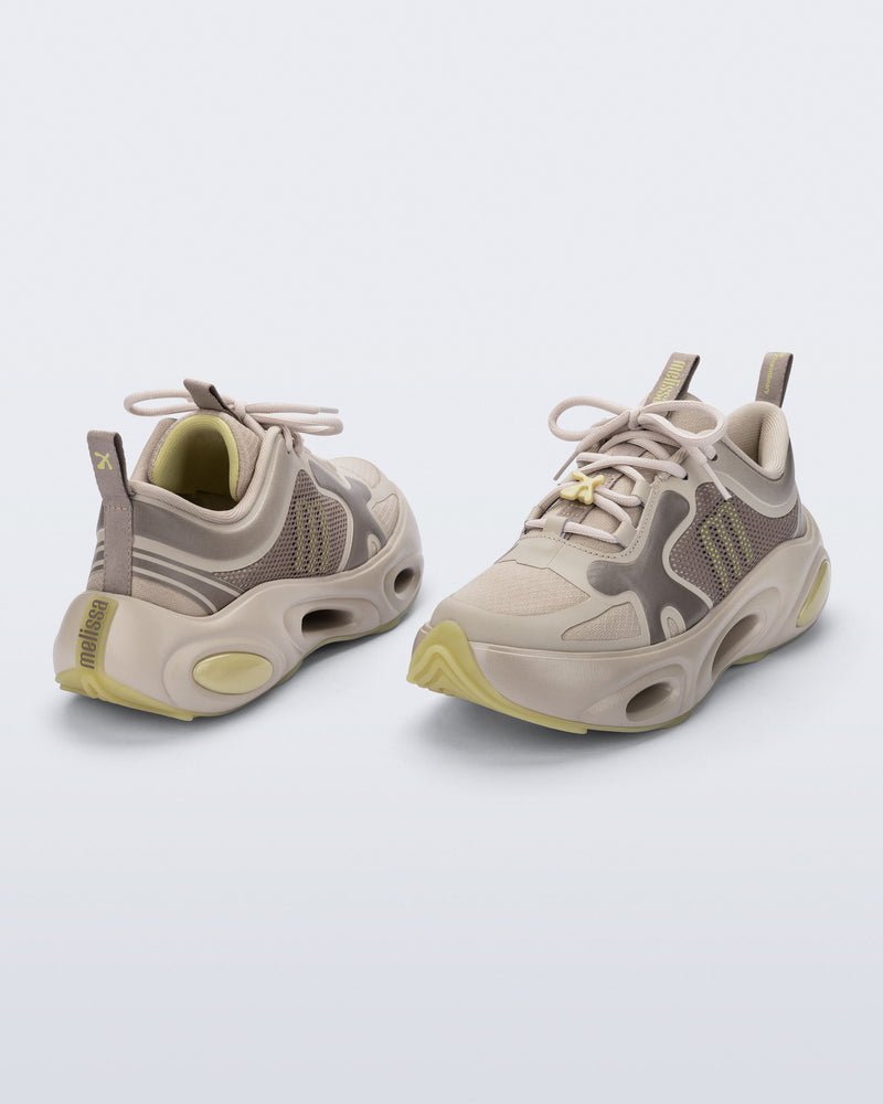 Back and angled view of a pair of beige X Loop sneakers