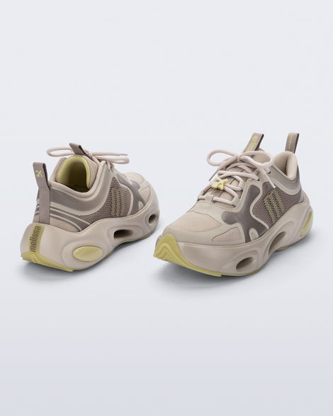 Back and angled view of a pair of beige X Loop sneakers