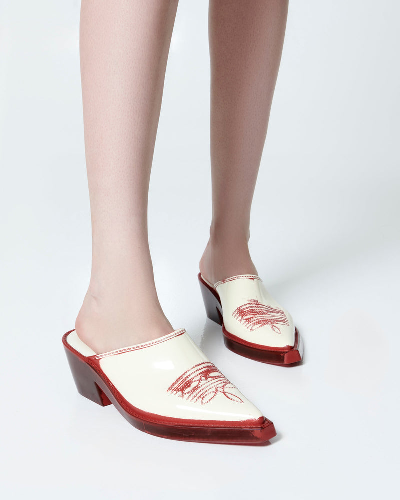 Model's legs wearing a pair of beige with red heel and accents Texas Mule heels