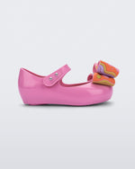 Side view of a pink with multi-color patterned bow Ultragirl Wonderland baby flat