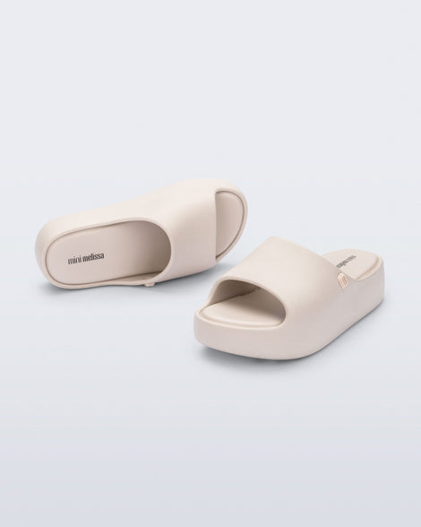 Angled top and front view of a pair of beige Free Platform Slide kids sandals