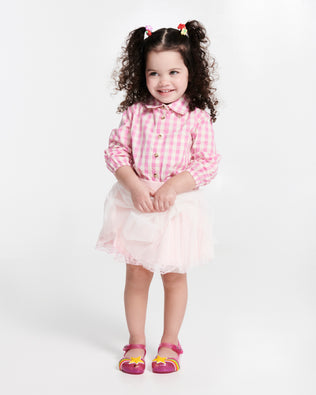 Child model in a pink shirt and skirt wearing a pair of glitter pink Ultragirl Colors baby flats with yellow star and rainbow on top