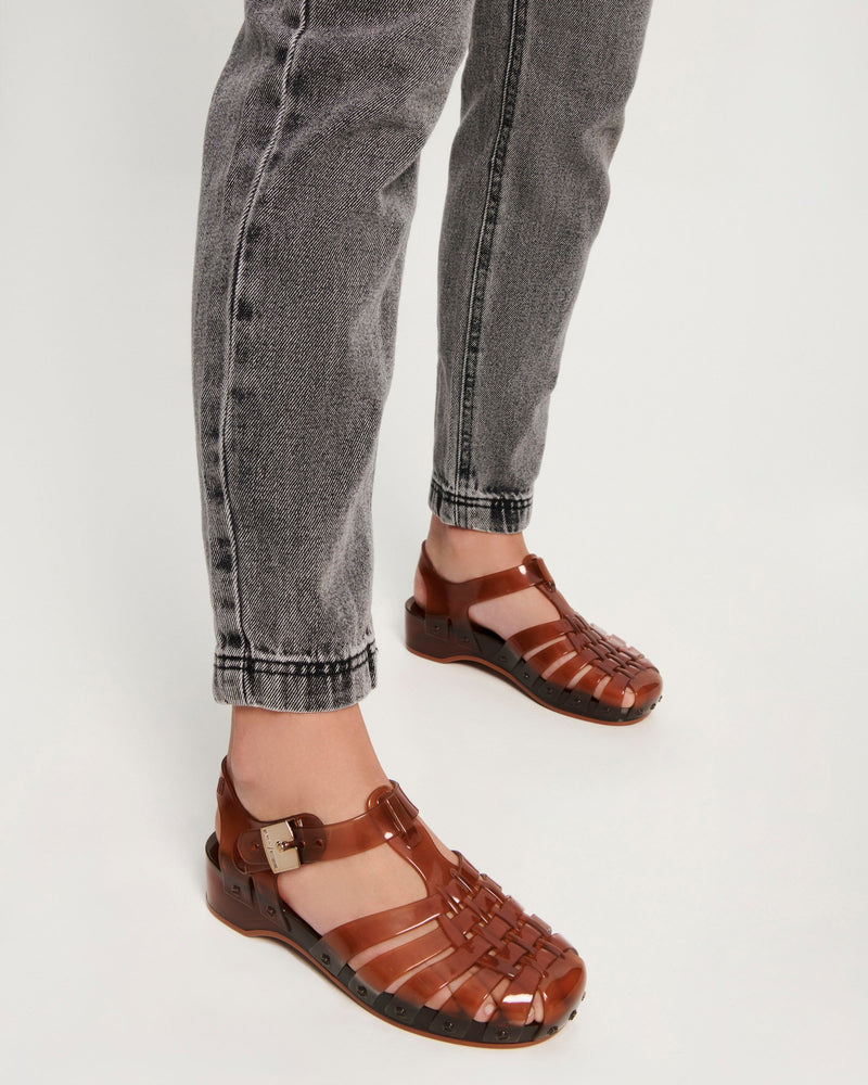Model's legs wearing a pair of clear brown Possession Pescura + Scholl fisherman sandals