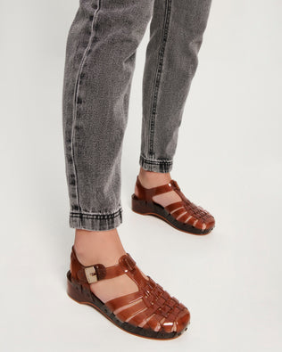 Model's legs wearing a pair of clear brown Possession Pescura + Scholl fisherman sandals