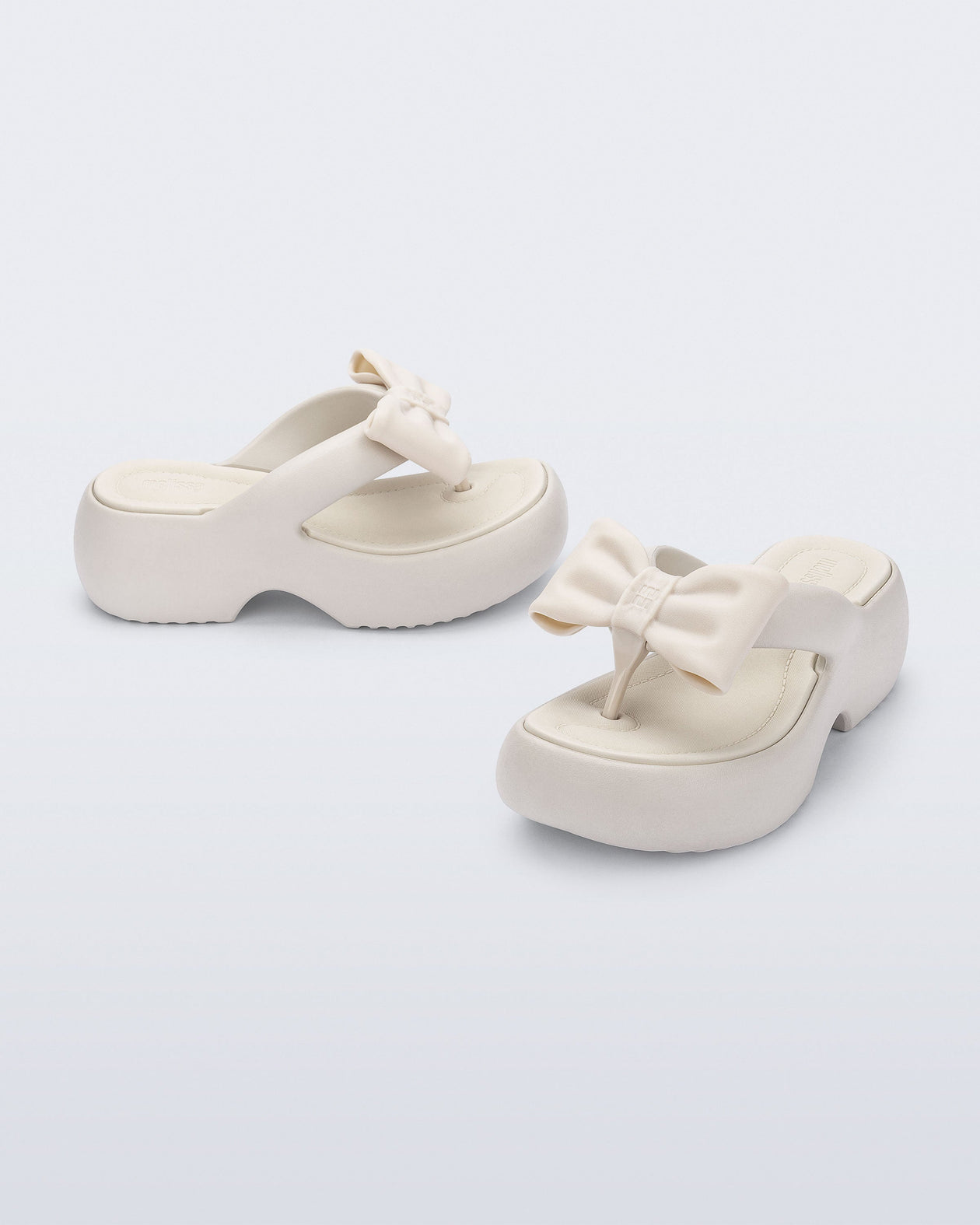 Side and angled view of a pair of beige Free Fuzzy Platform flip flops