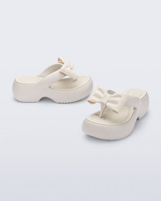 Side and angled view of a pair of beige Free Fuzzy Platform flip flops