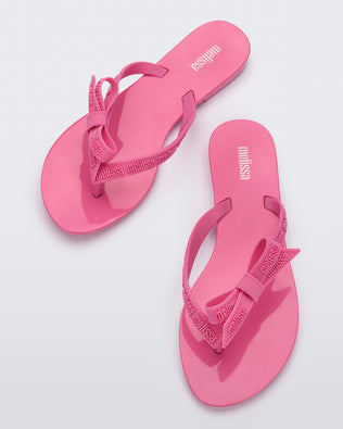 Top view of a pair of pink Harmonic M Lover adult flip flop with Melissa logo on strap