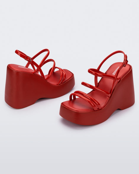 Angled view of a pair of red Jessie platform wedge sandals with side buckle ankle strap