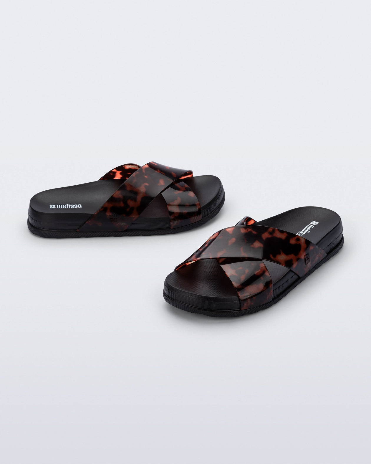 Side and angled view of a pair of black/tortoise Cozy Cross sandals with crisscross top straps