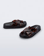 Side and angled view of a pair of black/tortoise Cozy Cross sandals with crisscross top straps