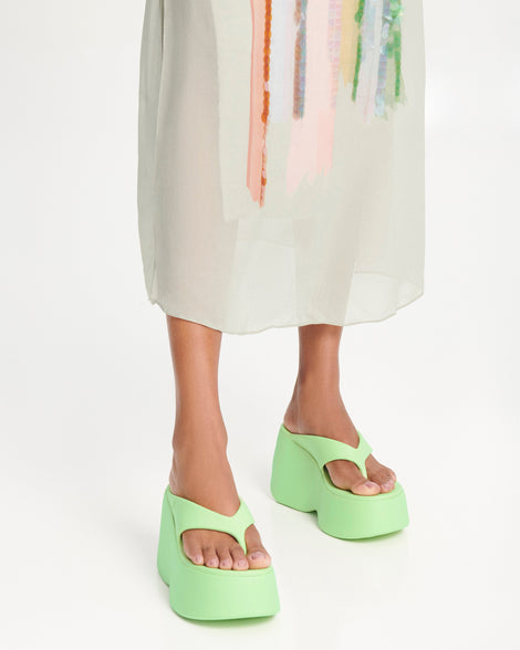 Model's legs wearing a pair of green Free Thong  Wedge Platform heels