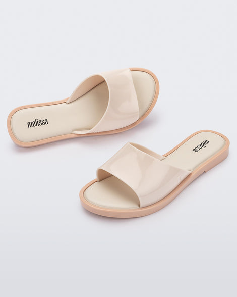 An angled side and top view of a pair of beige tortoiseshell Melissa Miranda slides