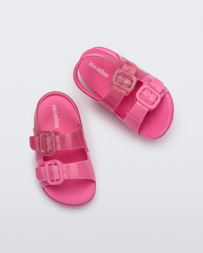 Top view of a pair of pink glitter Mini Melissa Cozy sandals with two front straps with buckle detail