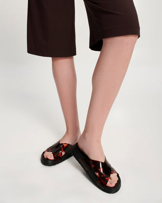 Model's legs in a pair of black/tortoise Cozy Cross sandals with crisscross top straps