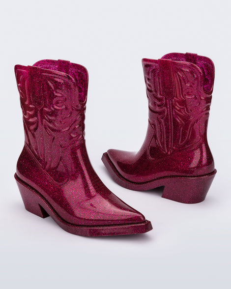Angled view of a pair of glitter pink Texas boots with pointed toe.