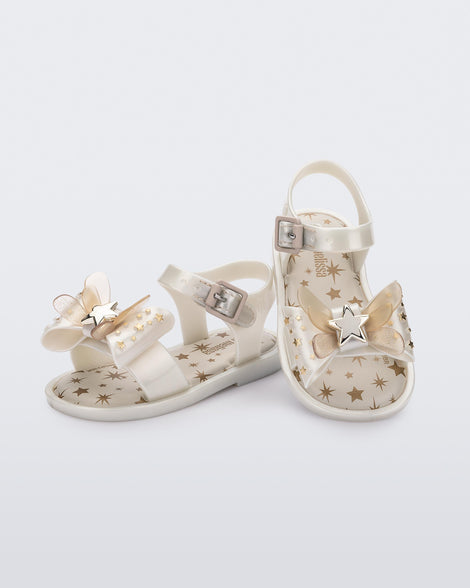 Angled view of a pair of Mini Melissa Mar Sandals with star print for baby in white with butterfly bow applique and velcro closure on ankle strap.