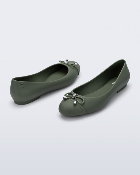 An angled back and side view of a pair of green Melissa flats with bow detail with gold accents on the bow