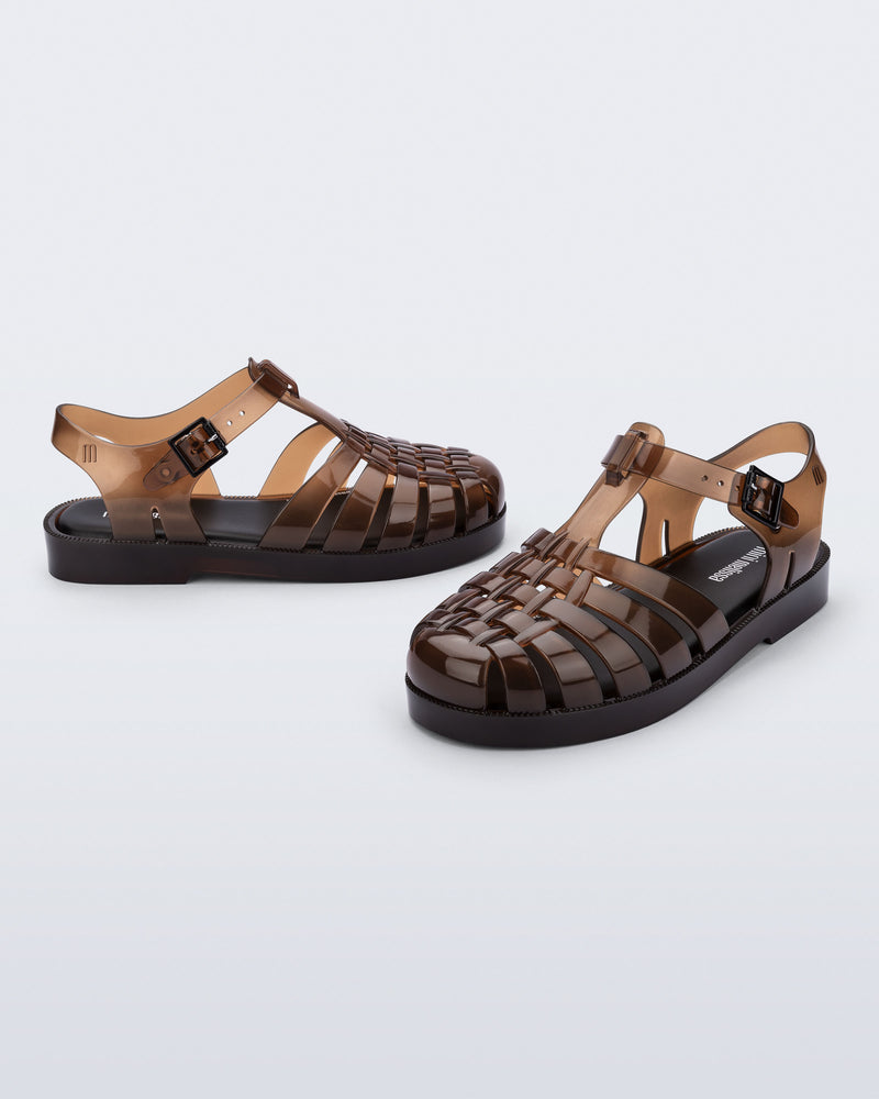 Side and angled view of a pair of transparent brown Possession kids sandals