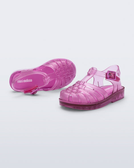 Top and angled view of a pair of transparent pink Possession fisherman baby sandals