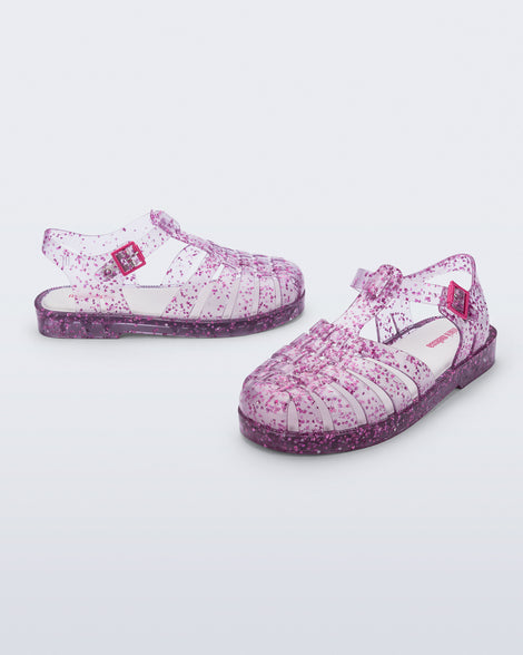 Side and angled view of a pair of clear Possession kids sandals with pink heart glitter