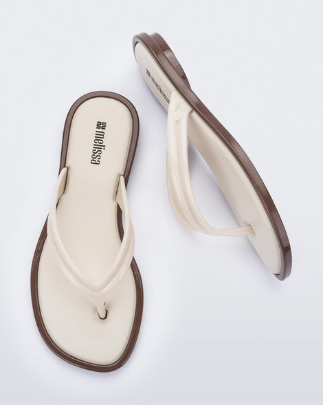 Side and top view of a pair of beige Wave Flip Flops with small heel and brown sole