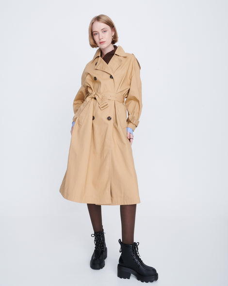 Model in a tan trench coat wearing a pair of black Track Boot with small heel and black laces
