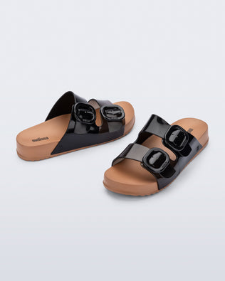 Angled view of a pair of black Cozy slides with beige soles