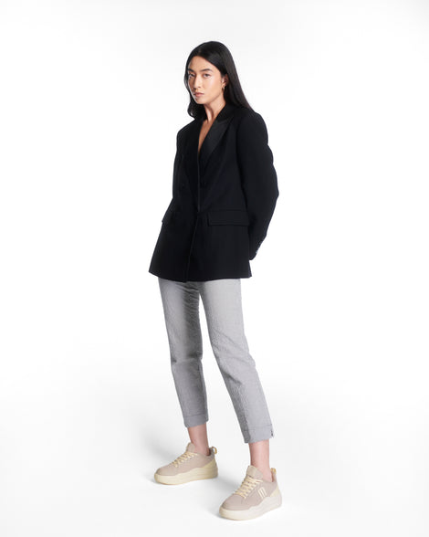 Model in grey pants and black coat wearing a pair of beige X Mood sneakers