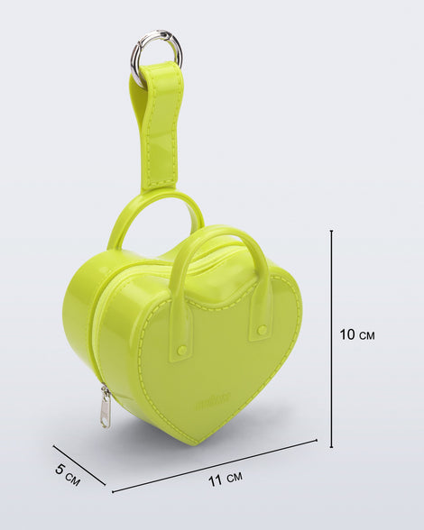 Angled view of a green Heartbeat Pocket bag charm with measurements of 11cm x 5cm x 10cm