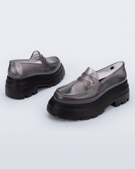 Angled view of a pair of transparent smoke Royal High + Undercover platform loafers with black sole. 