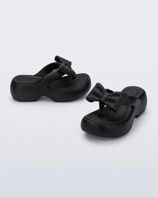 Side and angled view of a pair of black Free Fuzzy Platform flip flops