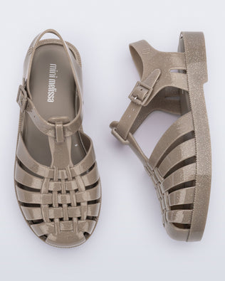 Side and top view of a pair of glitter beige kids Possession fisherman style sandals.