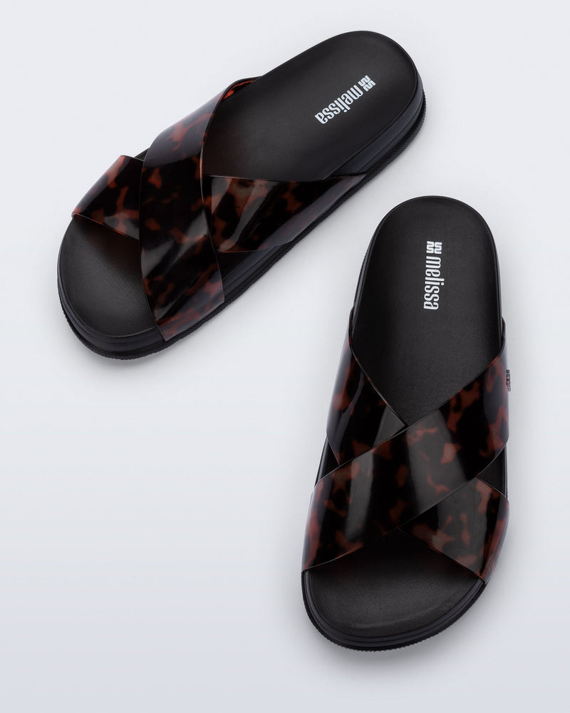 Top view of a pair of black/tortoise Cozy Cross sandals with crisscross top straps