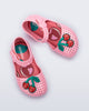 Top view of a pair of pink Pop baby flats with two red cherries