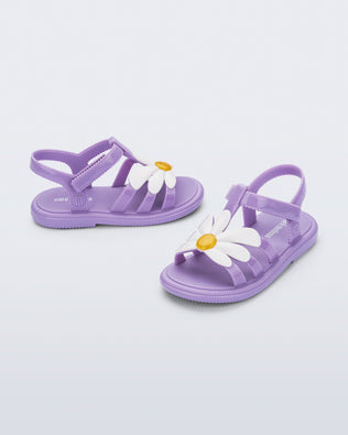 Side and angled view of a pair of purple Hip Bloom sandals with a white flower on top
