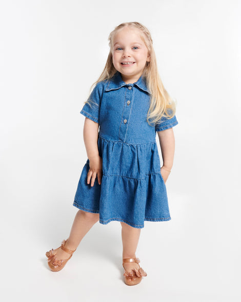 Child model in a blue dress wearing a pair of beige glitter Ultragirl Butterfly baby flats with butterflies on top