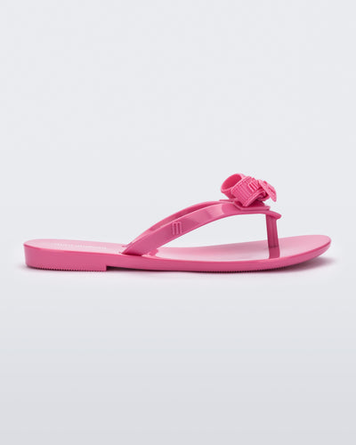 Side view of a pink Harmonic M Lover kids flip flop with Melissa logo on bow