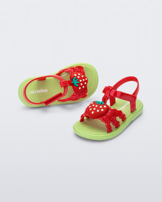 Angled view of a pair of red baby Hip Sandals with red strawberry and green sole