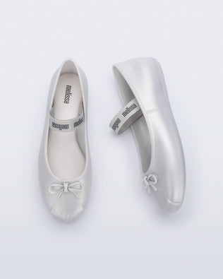 Side and top view of a pair of pearly white Sophie flats with top elastic strap and small bow