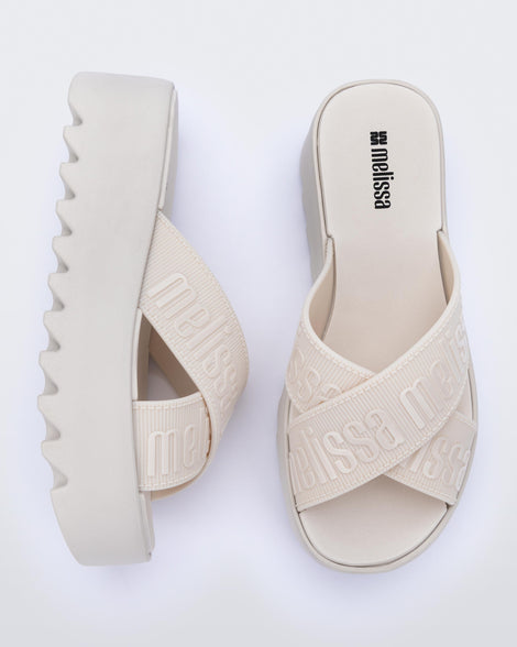 Top and side view of a pair of beige M Lover Cross Strap platform slides