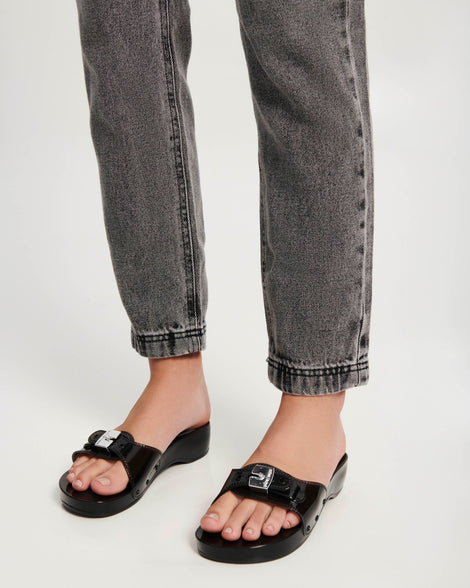 Model's legs wearing a pair of black Pescura Heel + Scholl slides with top buckle