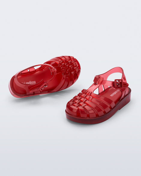 Angled and top view of a pair of clear red Possession baby sandals