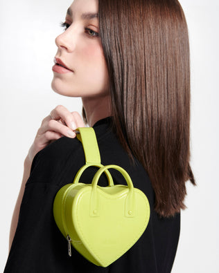 Model in a black shirt holding in her hand the green Heartbeat Pocket charm