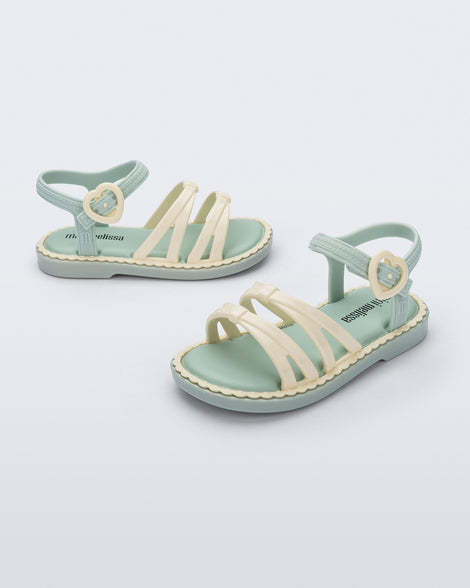 Side and angled view of a pair of green Aurora baby sandals with beige trim, straps and buckle
